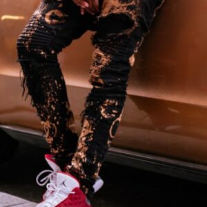 Black pants with bleach-stain pattern, paired with white sneakers.