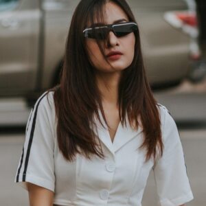 Person wearing a cropped white T-shirt and sunglasses, standing outdoors in daylight.