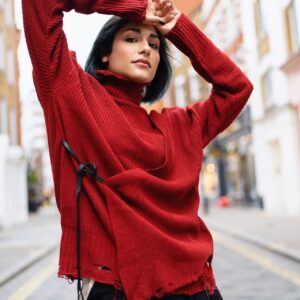 Person wearing a bright red oversized sweater with distressed hem details.