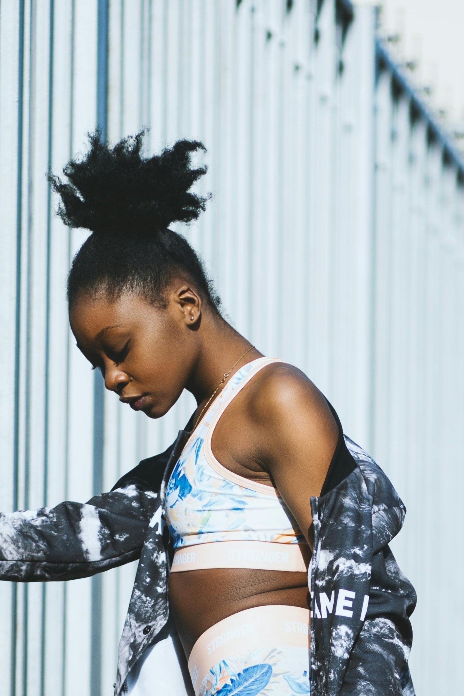 Model wearing blue sports top, leggings and a black and white jacket.