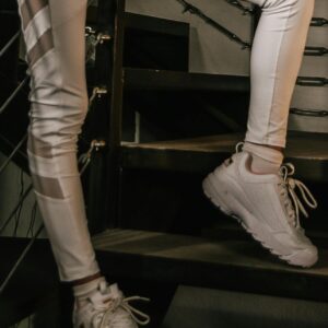 White high-waisted leggings paired with sneakers in an indoor staircase.