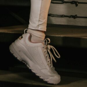 Close-up of white chunky trainers worn with white leggings.