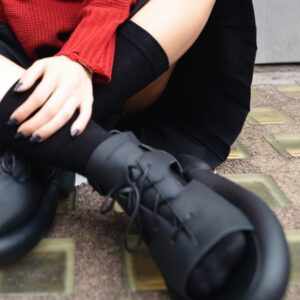 Black open-toe shoes styled with socks, worn with casual streetwear outdoors.