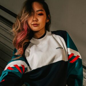 Person wearing a loose, color-block sweatshirt with pink, blue, and white details, posing casually.